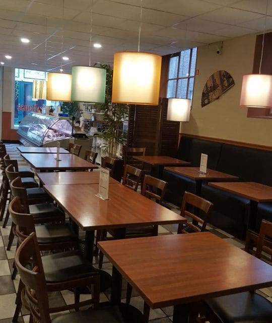 Tafels binnen bij de toko in Deventer onder gekleurde hanglampen