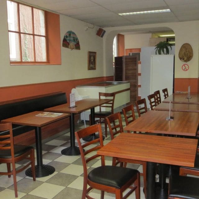 De inrichting van Java House met bank, houten tafels en geblokte vloer